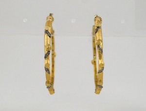 A pair of gold hoop earrings with black stones.