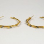 A pair of gold hoop earrings with black diamonds.