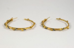 A pair of gold hoop earrings with black diamonds.
