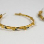 A pair of gold hoop earrings with black and white diamonds.