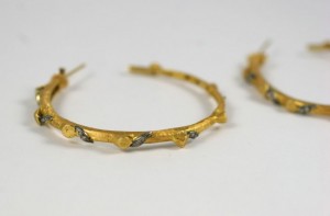 A pair of gold hoop earrings with black and white diamonds.