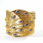 A gold bracelet with blue stones on it.