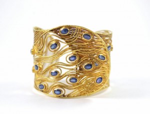 A gold bracelet with blue stones on it.