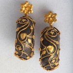 A pair of earrings with gold and black designs.