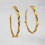 A pair of gold hoop earrings with black stones.