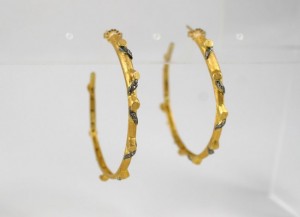 A pair of gold hoop earrings with black stones.