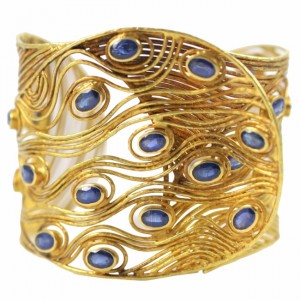A gold bracelet with blue stones on it.