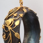 A black and gold bracelet hanging from a chain.