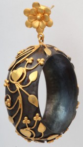 A black and gold bracelet hanging from a chain.