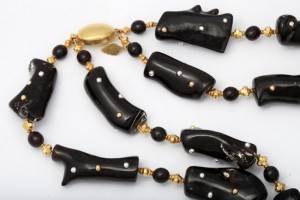 A black and gold necklace with white beads.