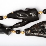 A black necklace with gold beads and three large pieces of animal head.