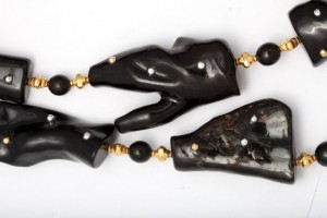 A black necklace with gold beads and three large pieces of animal head.