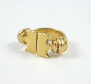 A gold ring with a t shaped design on it.