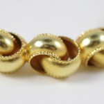 A close up of gold beads on a white surface