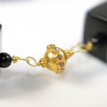 A close up of the gold bead on a black necklace