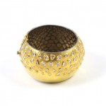 A gold colored metal bowl with some diamonds on it