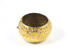 A gold colored metal bowl with some diamonds on it