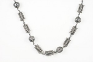 A silver chain with various shapes and sizes of beads.