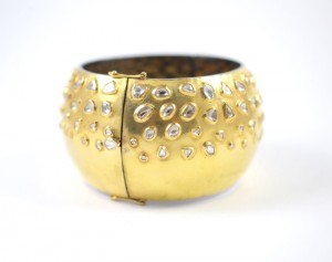 A gold bangle with clear stones on it.