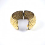 A gold bracelet with some small holes on it