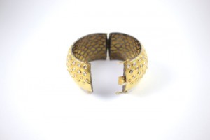 A gold bracelet with some small holes on it