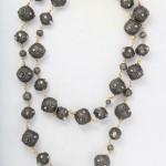 A long necklace with black beads and gold chains.