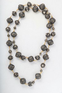 A long necklace with black beads and gold chains.