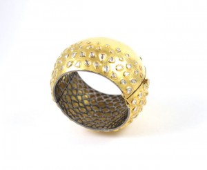 A gold bracelet with white stones on it.
