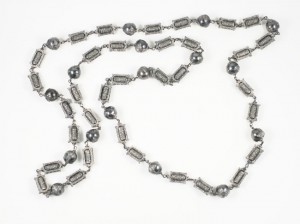 A long silver chain with beads and metal chains.