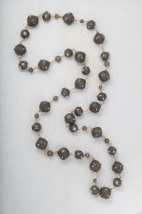A long necklace with black beads and gold accents.