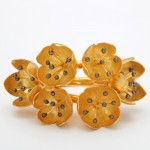 A gold bracelet with six flowers and black diamonds.