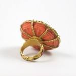 A gold ring with an orange stone on it.
