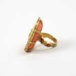 A gold ring with a pink and red stone.