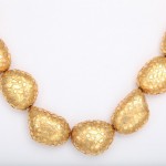 A gold necklace with eight large beads.