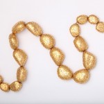 A gold necklace is shown on top of the table.