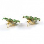 A pair of green and gold earrings on top of a white surface.