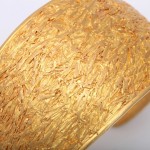 A close up of the gold leaf on the side of a bracelet