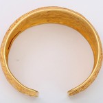A gold bracelet with a small hole in it.