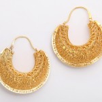 A pair of gold earrings with intricate design.