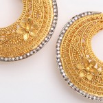 A pair of gold and diamond earrings with floral design.