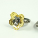 A ring with a flower made of gold and silver.
