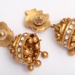 A pair of gold earrings with pearls and diamonds.