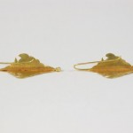 A pair of gold leaf earrings on white background.