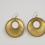 A pair of gold earrings with a round design.