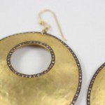 A pair of gold earrings with diamonds on them.
