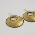 A pair of gold earrings sitting on top of a table.