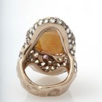 A gold ring with an orange stone and white stones.