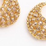 A pair of gold earrings with clear stones.