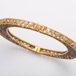 A gold and diamond bracelet with intricate design.