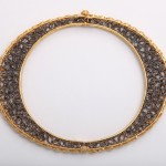 A gold and diamond necklace with a circular frame.